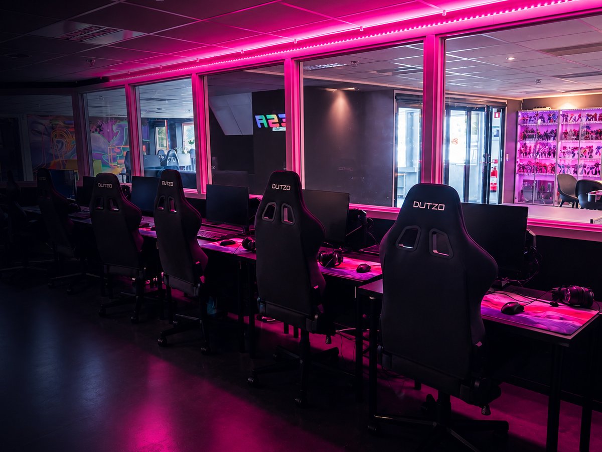 Gamingplatser i E-Sports Academys lokal med rosa neonljus